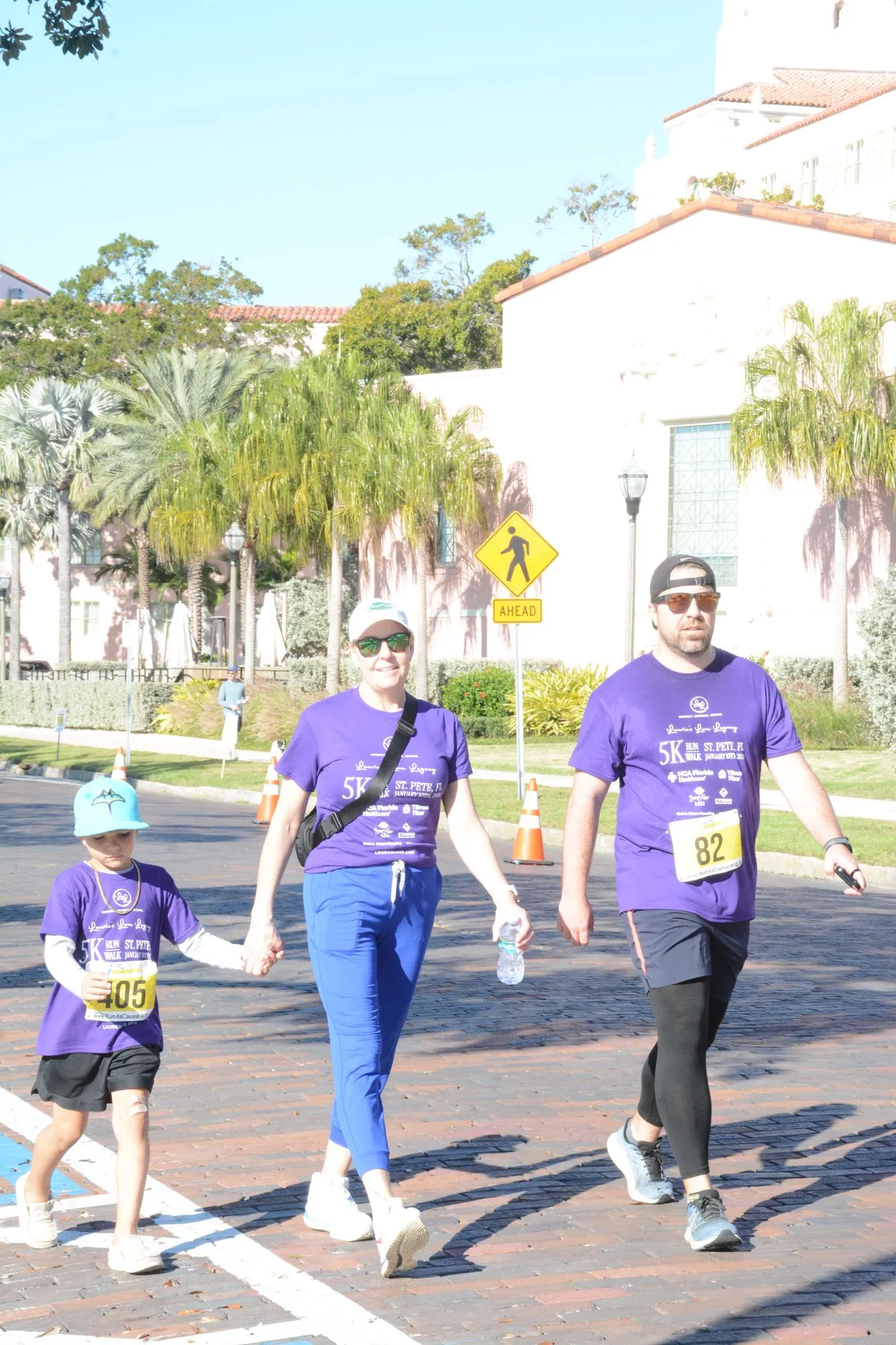 A child walks the 2026 course with two adults in purple Laurie’s Love shirts